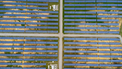 Aerial view of solar power plant on green field. Solar panels system for solar power generation. Green energy for sustainable development to prevent climate change and global warming to protect earth.