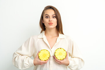 Young Caucasian smiling woman holding slices pineapple over white background, breast health concept
