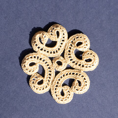 Handmade crochet lace in beige for placemats on a royal blue background. Flat lay.