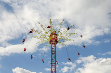 People on a carousel on a high tower against the blue sky.