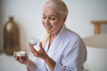 A woman in a white robe with a face cream