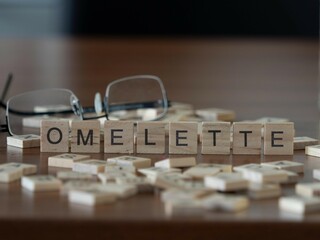 omelette word or concept represented by wooden letter tiles on a wooden table with glasses and a book