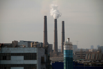 Clouds of smoke from the smokestacks of an industrial plant pollutes the air in a suburban area
