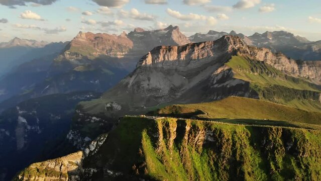 Spinning flyover around the summit of Niederbauen Chulm during a golden summer sunset in the Swiss Alps with a view of the fjords of Lake Lucerne, Mythen, Rigi, Burgenstock, Pilatus (sped up 4x)