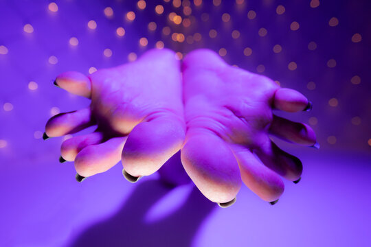 Bottom view of person fetish feet soles with long toenails toes in colorful lights