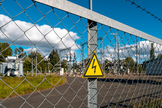 Yellow triangle with lightning behind metal mesh fence