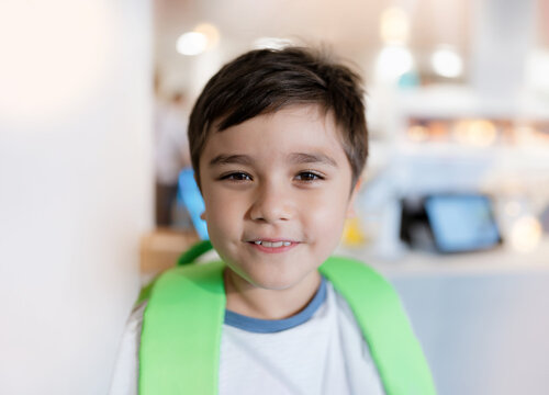 Portrait Kid looking at camera with smiling face standing alone with blurry payment counter background, Head shot happy Child boy standing at front of blurry image of toy shop in department store