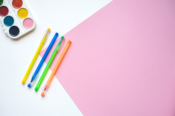 A set of stationery on a white and pink background, pens of different colors and watercolor