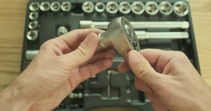 Mechanic removes the head from the ratchet and puts everything in the toolbox on the table. Top view, close-up, first-person view.