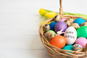 Wicker baskets with bright colorful eggs and with text Happy Easter and flower