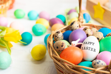 Fototapeta na wymiar Wicker baskets with bright colorful eggs and with text Happy Easter and flower