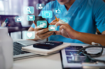 Doctor working with laptop and digital smartphone in office at hospital in morning light. Social...