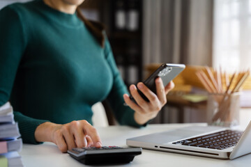 Fototapeta premium Investors have to calculate investment cost calculator and hold a mobile phone in hand.