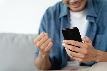 Happy excited man looking at mobile phone, man receiving good news using smartphone at home.