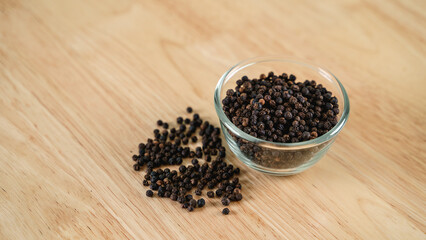 Black pepper in a glass bowl on the wooden table. food, spice, seasoning Concept.