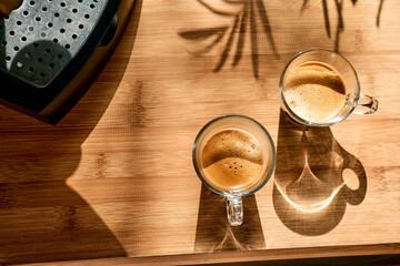Two glass cups of aromatic hot drink espresso, prepared in espresso coffee machine in the kitchen at home. Awakening drink. Morning habit.