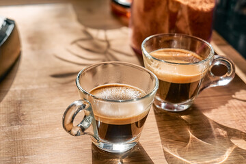 Two glass cups of aromatic hot drink espresso, prepared in espresso coffee machine in the kitchen at home. Awakening drink. Morning habit.