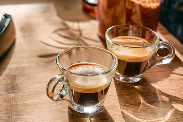 Two glass cups of aromatic hot drink espresso, prepared in espresso coffee machine in the kitchen...
