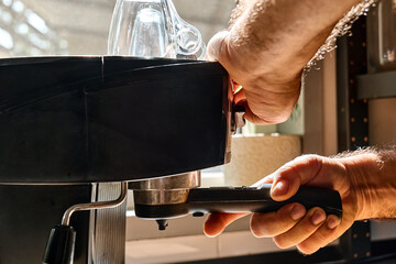 Hands of man making espresso in espresso coffee machine in the kitchen at home. Awakening hot drink. Morning habit.
