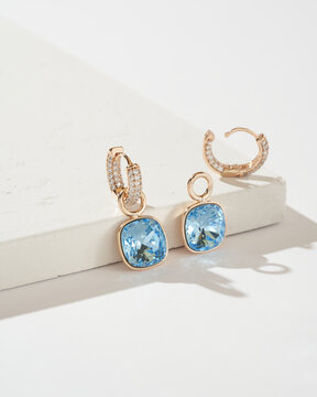 Golden earrings with light blue crystals and diamonds isolated on white background. Fashionable jewelry.