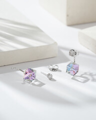 Golden earrings with square shaped  blue, iridescent crystals and diamonds isolated on white background. Fashionable jewelry.