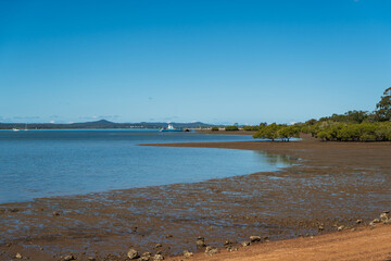 View from the shoreline at low tide across to Macleay Island, and Stradbroke Island in the distance. Vehicular ferry. Redland Bay, Queensland, Australia.