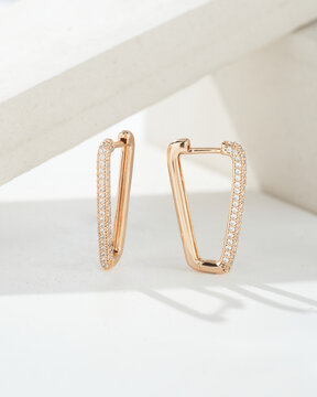 Golden earrings with white crystals and diamonds. Beautiful earrings on white background. Women accessories. Fashionable jewelry.