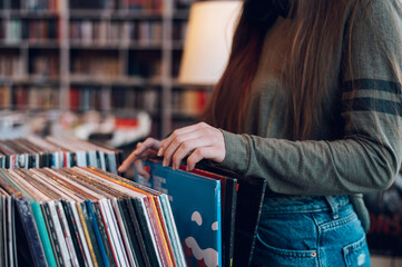 Mains de femme choisissant un disque vinyle dans un magasin de disques