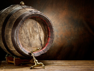 Wooden wine or beer barrel with metal hoops on the wooden table at the brown background.