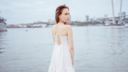 Fototapeta na wymiar City portrait of beautiful young woman in white dress.
