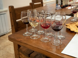 Glasses with different red and white wines on wooden table. Tasting wine.
