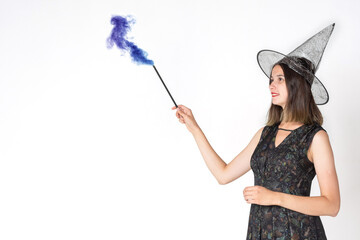 A beautiful teen girl in a witch costume, wearing a hat, with a magic wand with swirling colored...