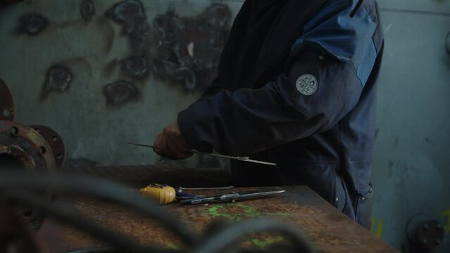 close up of a mans hands in a workshop cutting trough a piece of cardboard.