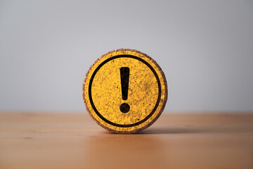 Yellow exclamation caution sign or warning symbol print screen on round wooden block on dark...