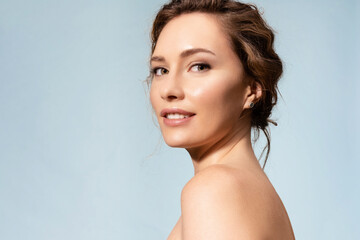 Pretty female with healthy glowing moisturized skin, bare shoulders looking at camera. Studio...