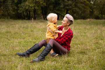 Fototapeta premium Mother with her little son sitting in autumn or summer forest