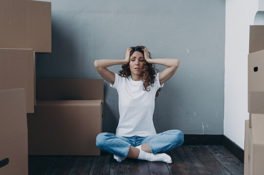 Tired puzzled young woman is under stress due to hard relocation day. Moving company advertising