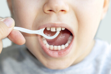 little boy is cleaning his teeth with a toothpick. plastic dental floss.close up photo.kid with...