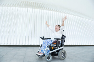 portrait of a happy disabled woman in a wheelchair laughing with open arms, concept of overcoming...