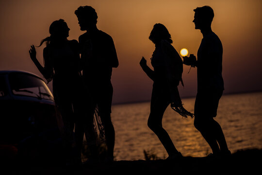 Photo of dreamy positive hippie people company dancing together enjoying sunset outside seaside beach