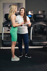 Fototapeta na wymiar Female instructor talking with plus size woman at the gym