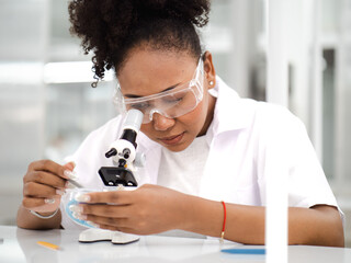 Female medical science student uses microscope for biochemistry education in research laboratory....