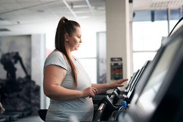Fototapeta na wymiar Plus size caucasian woman running on treadmill at gym