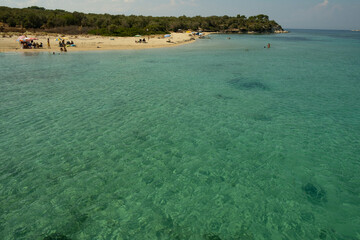 Beach with small boats and clear green water.
