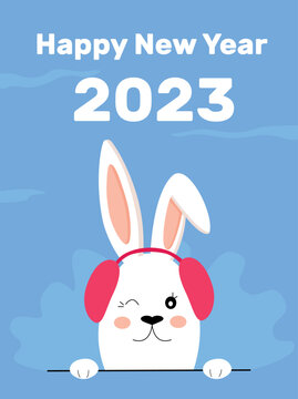 Chinese New Year 2023, year of the rabbit. Toy cute rabbit with hat with headphones against the background of snowflakes. Merry Christmas. New Year holidays