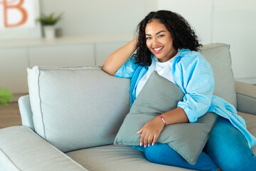 Fototapeta premium Happy African American Woman Sitting On Sofa At Home
