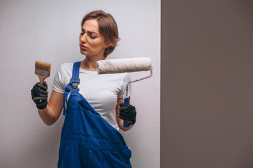 Repair woman holding painting roller and brush 