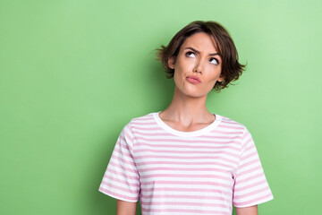 Photo of unsure bob hairdo young lady look up wear white striped t-shirt isolated on green color...