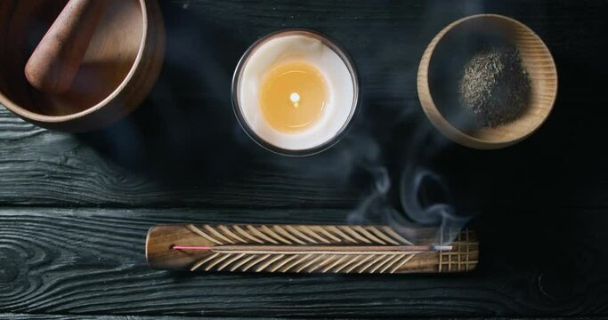 Incense stick smoldering in holder on black wooden table. Flat lay