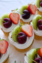 Butter cupcakes topped with strawberries, oranges and blueberries. Homemade bakery concept..